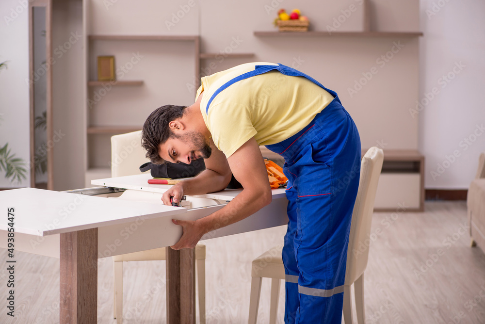 Young male carpenter repairing table at home