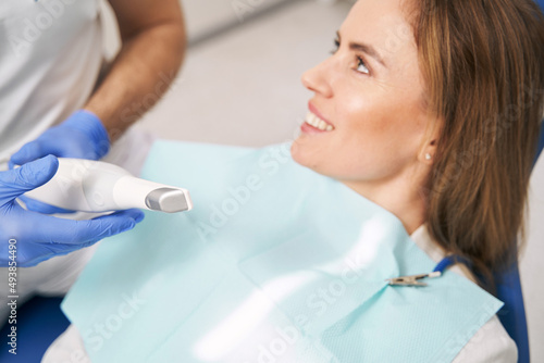 Doctor with dental device sitting next to woman in clinic