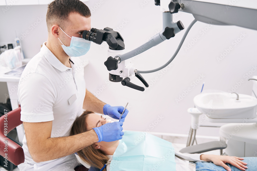 Obraz premium Dentist examining woman teeth with microscope in dental clinic