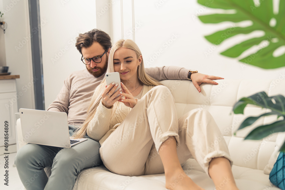 Young Caucasian couple working on the sofa with gadgets remote job . High quality photo
