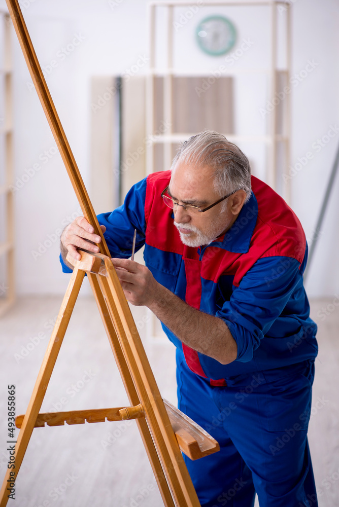 Obraz premium Old male carpenter repairing drawing easel
