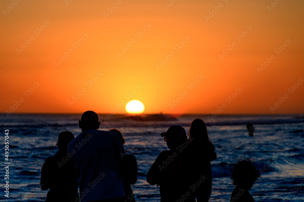 Silhouettes of people in front of a colorful sunset on the beach. Silhouettes of people in front of a colorful sunset on the beach.