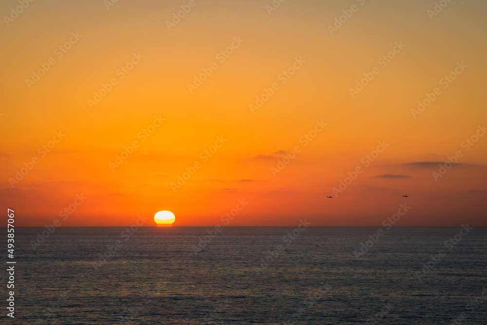 2022-03-20 A SUNSET OVER THE PACIFIC OCEAN WITH TWO HELICOPTERS FLYING PAST NEAR LA JOLLA CALIFORNIA