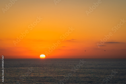 Fototapeta Naklejka Na Ścianę i Meble -  2022-03-20 A SUNSET OVER THE PACIFIC OCEAN WITH TWO HELICOPTERS FLYING PAST NEAR LA JOLLA CALIFORNIA