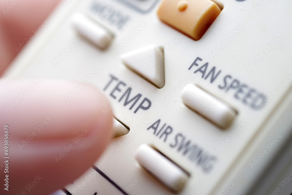 close up of a finger pressing a button on the remote control of air conditioner close up of a finger pressing a button on the remote control of air conditioner