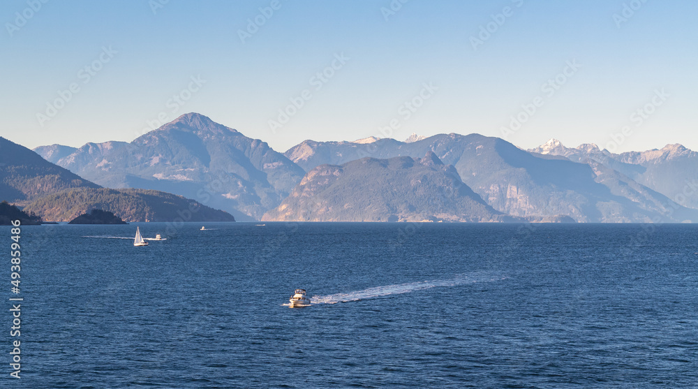 Boat in the sea in the sunlight over beautiful big mountains background, summer adventure, active vacation