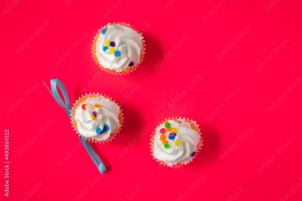 Three vanilla icing cupcakes on red background Three vanilla icing cupcakes on red background