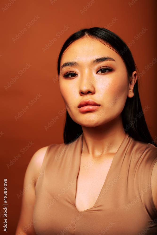 young pretty asian woman cheerful smiling posing on warm brown background, lifestyle people concept young pretty asian woman cheerful smiling posing on warm brown background, lifestyle people concept