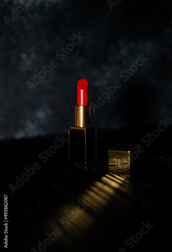 red lipstick in a dark gold case on a dark background