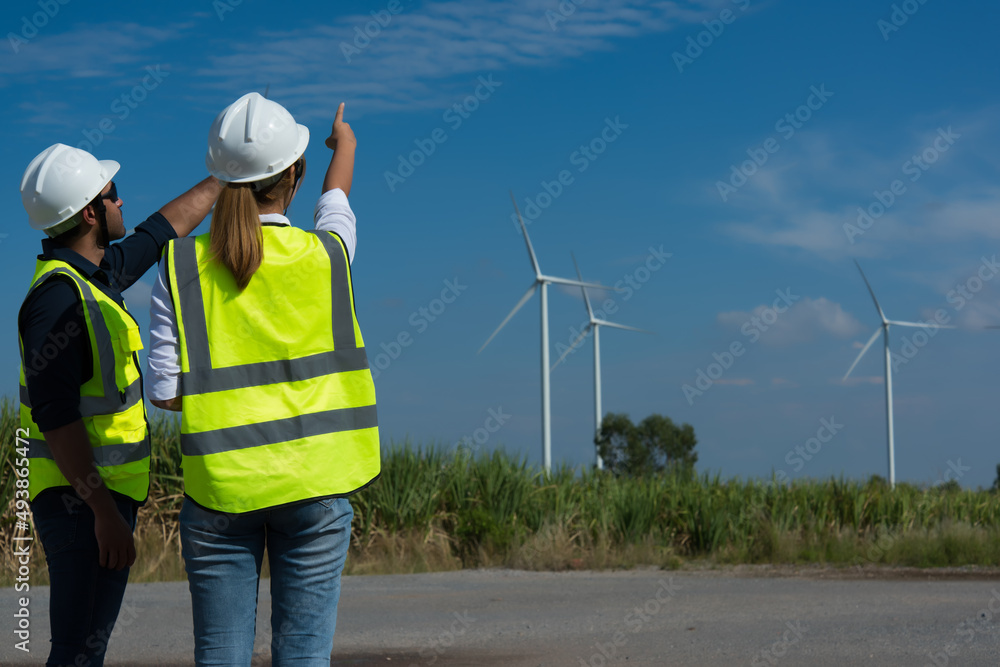 Back view of two engineers discussing against turbines on wind turbine farm. Back view of two engineers discussing against turbines on wind turbine farm.