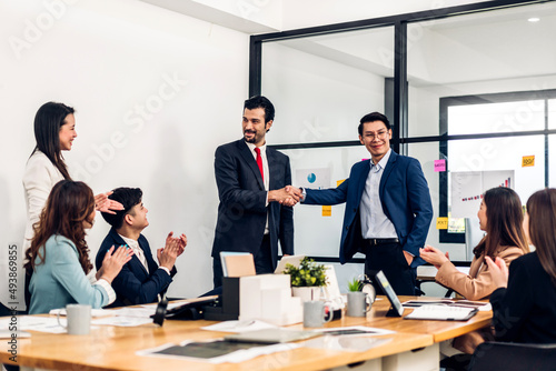 Image two asian business partners in elegant suit successful handshake together in front of group of casual business clapping hands in modern office.Partnership approval and thanks gesture concept