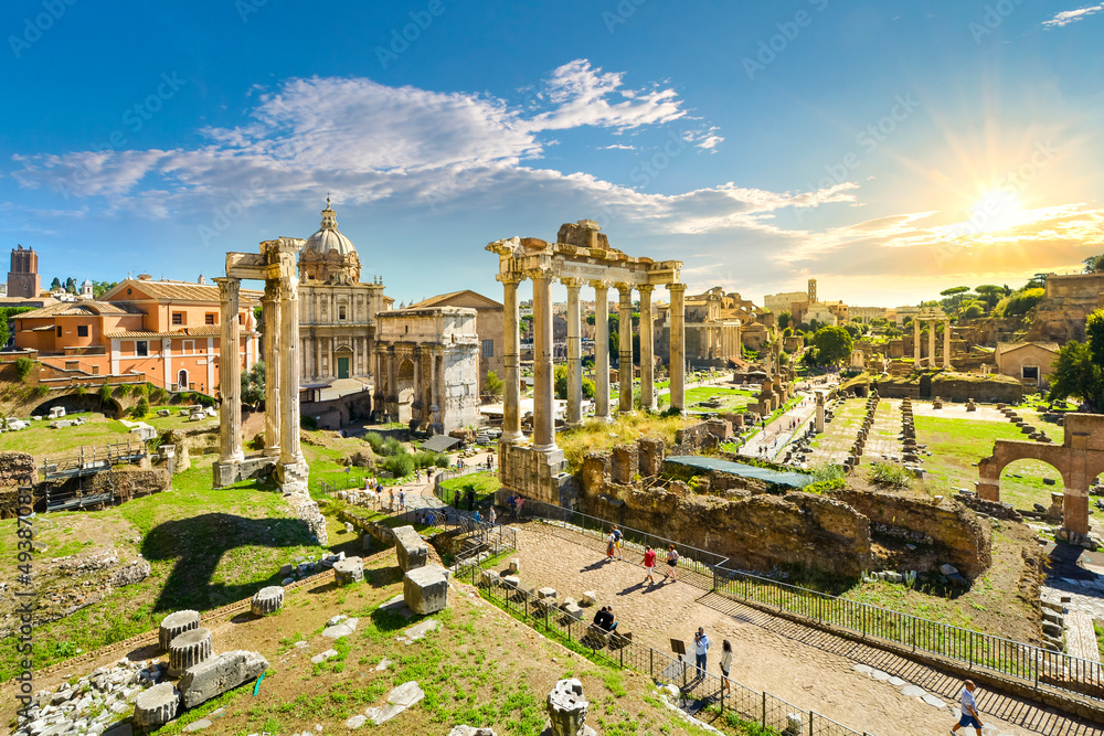 The ancient Roman Forum with the sun setting above the Colosseum in the historic center of Rome, Italy. View facing northeast from above the Portico Dii Consentes.