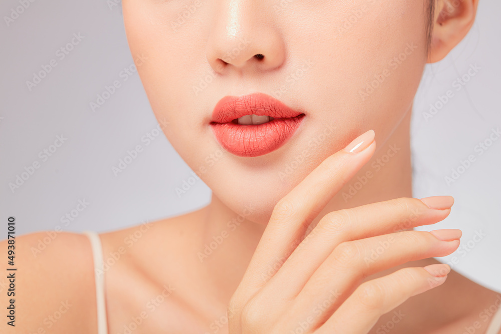 A close view of model showing lip posing with hand for cosmetic advertising