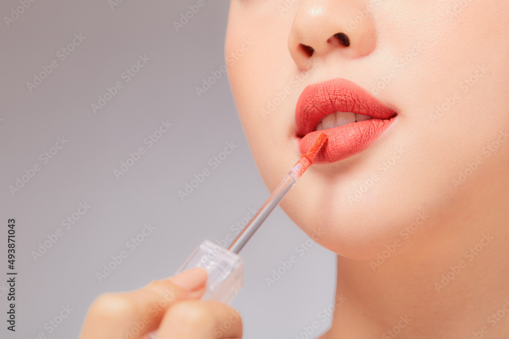 Front view of model using lipstick in white background for cosmetic advertising Front view of model using lipstick in white background for cosmetic advertising
