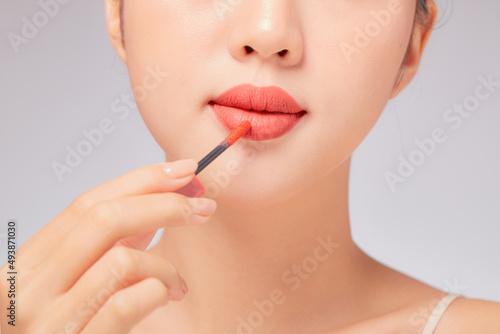 Front view of model using lipstick in white background for cosmetic advertising 