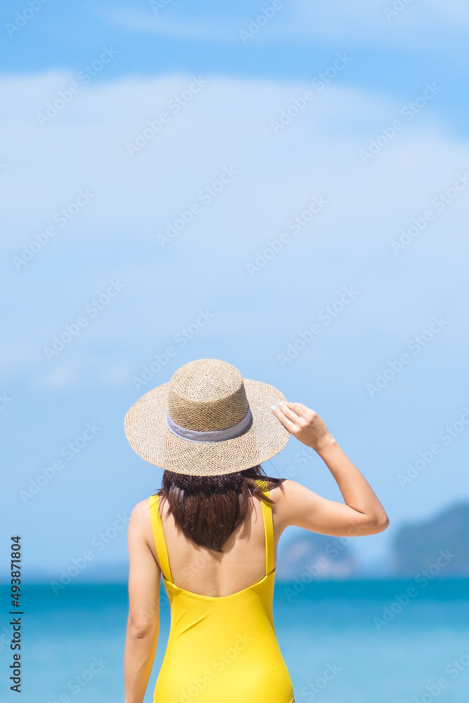 Woman tourist in yellow swimsuit and hat, happy traveler sunbathing at Paradise beach on Islands. destination, wanderlust, Asia Travel, tropical summer, vacation and holiday concept