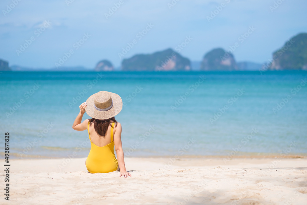Woman tourist in yellow swimsuit and hat, happy traveler sunbathing at Paradise beach on Islands. destination, wanderlust, Asia Travel, tropical summer, vacation and holiday concept Woman tourist in yellow swimsuit and hat, happy traveler sunbathing at Paradise beach on Islands. destination, wanderlust, Asia Travel, tropical summer, vacation and holiday concept