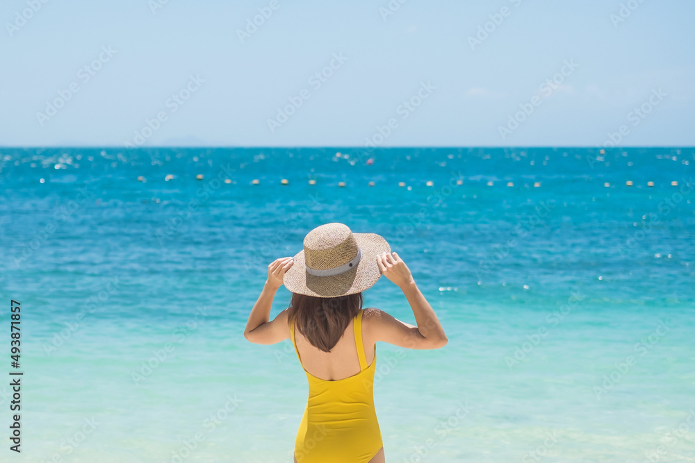 Woman tourist in yellow swimsuit and hat, happy traveler sunbathing at Paradise beach on Islands. destination, wanderlust, Asia Travel, tropical summer, vacation and holiday concept Woman tourist in yellow swimsuit and hat, happy traveler sunbathing at Paradise beach on Islands. destination, wanderlust, Asia Travel, tropical summer, vacation and holiday concept