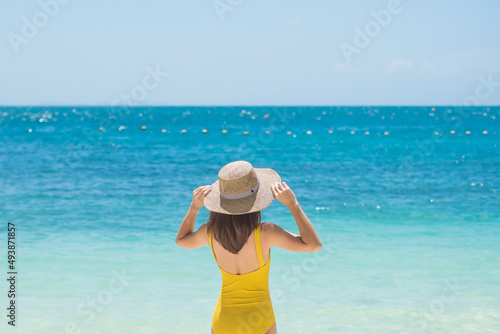 Woman tourist in yellow swimsuit and hat, happy traveler sunbathing at Paradise beach on Islands. destination, wanderlust, Asia Travel, tropical summer, vacation and holiday concept © Jo Panuwat D