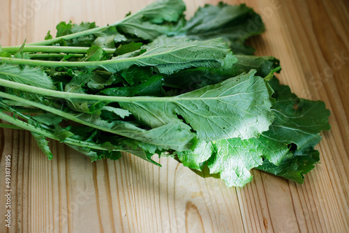 Close up photo of Fresh white turnip greens sitting on wooden table. Beautiful soft sunlight.