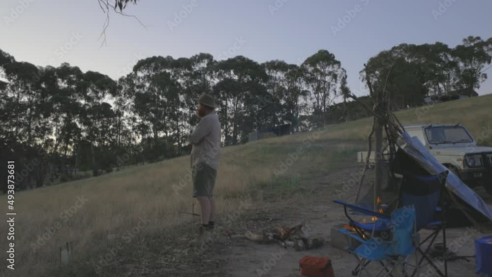 Wide shot of a farmer smoking a tobacco pipe by his campsite on a farm property. Wide shot of a farmer smoking a tobacco pipe by his campsite on a farm property.