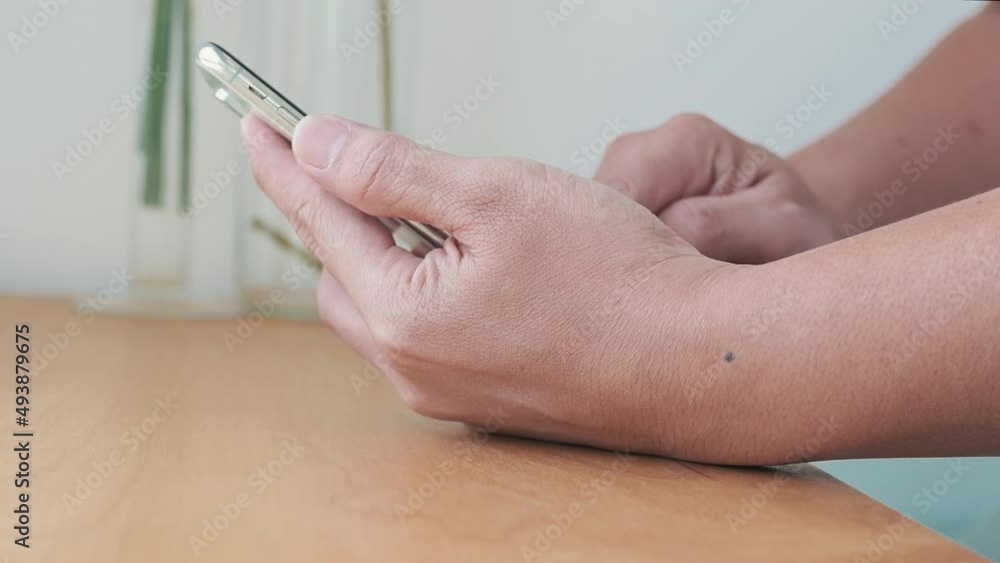 close up of a person using a smartphone on wood table. close up of a person using a smartphone on wood table.