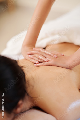 Hands of masseuse using oils when massaging back of female client