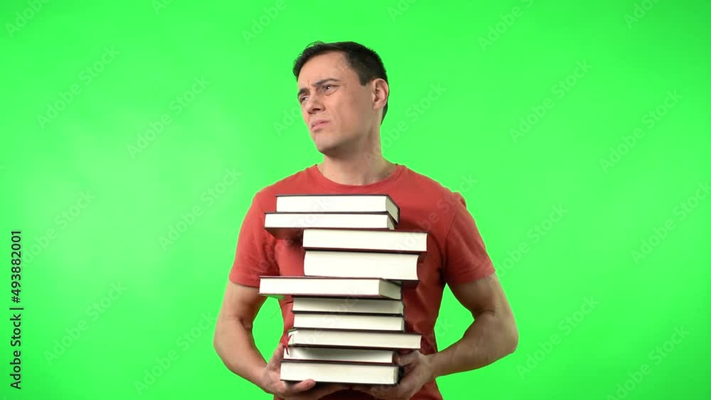 Exhausted man carrying pile of textbooks exhaling during exam preparation Exhausted man carrying pile of textbooks exhaling during exam preparation
