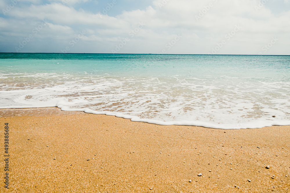 Fototapeta premium Low angle shot of beach waves with sky