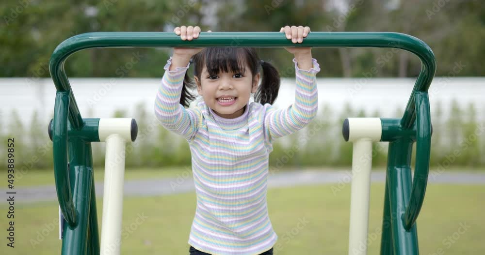 Asian little girl enjoy to playing on outdoor exercise equipment with smile, at playground Asian little girl enjoy to playing on outdoor exercise equipment with smile, at playground