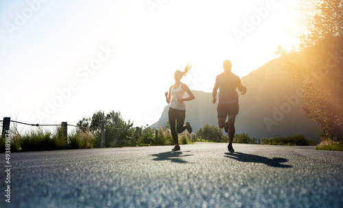 Theres one way to succeed and thats to give everything. Low angle shot of two people running on a tarmac road.