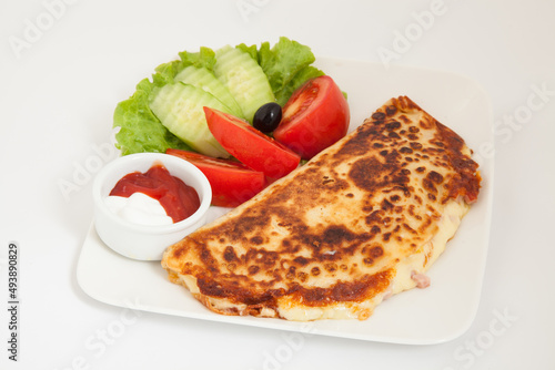 Classic omelet with cheese and tomatoes and cucumbers salad on a white plate