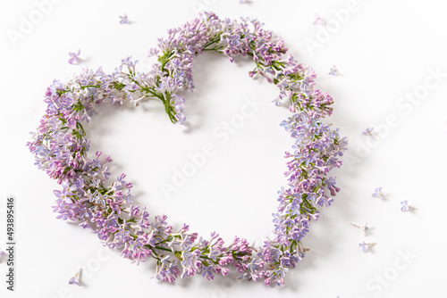 Beautiful heart made of lilac flowers on a white background. Springtime background, floral design. Love spring. Flat lay. Creative floral background. Greeting card, poster, print © Dina Photo Stories