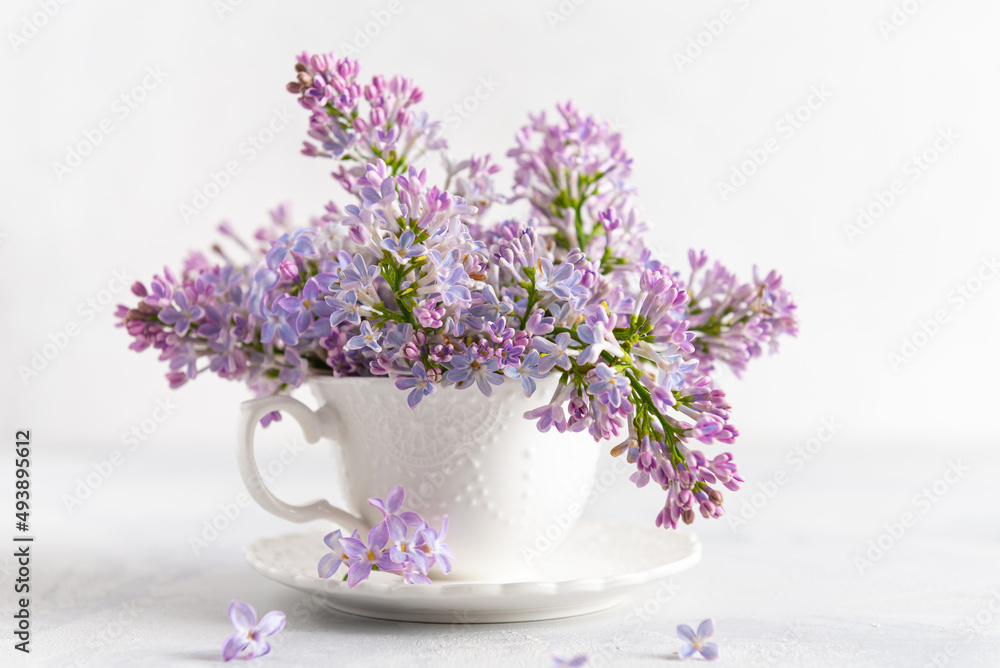 Spring floral background with lilacs in a cup. Decorative composition with a Bouquet of lilacs in a light kitchen interior. The concept of holidays and good morning wishes. Spring vibes
