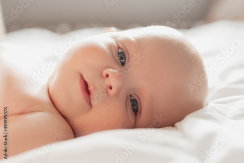 closeup portrait of a blue-eyed newborn baby lying on his back on a white sheet. happy carefree infancy. products for children, natural materials. space for text. High quality photo photo