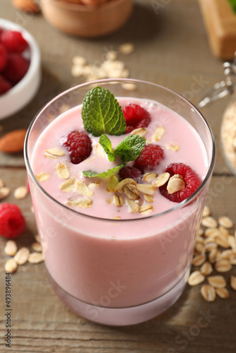 Glass of tasty raspberry smoothie with oatmeal and mint on wooden table