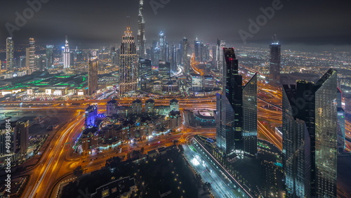 Aerial view of tallest towers in Dubai Downtown skyline and highway night timelapse.