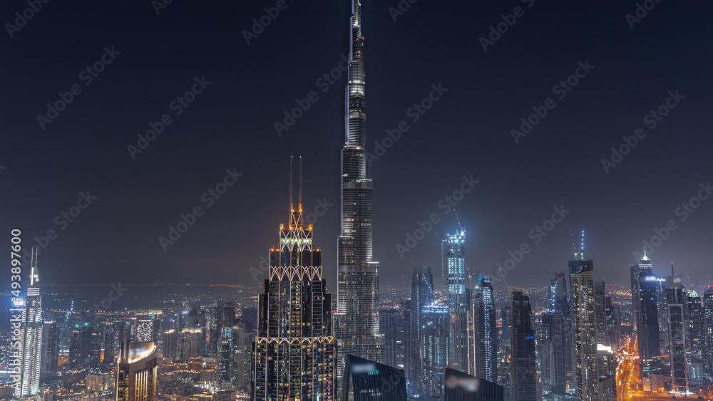 Fototapeta premium Aerial view of tallest towers in Dubai Downtown skyline and highway night timelapse.