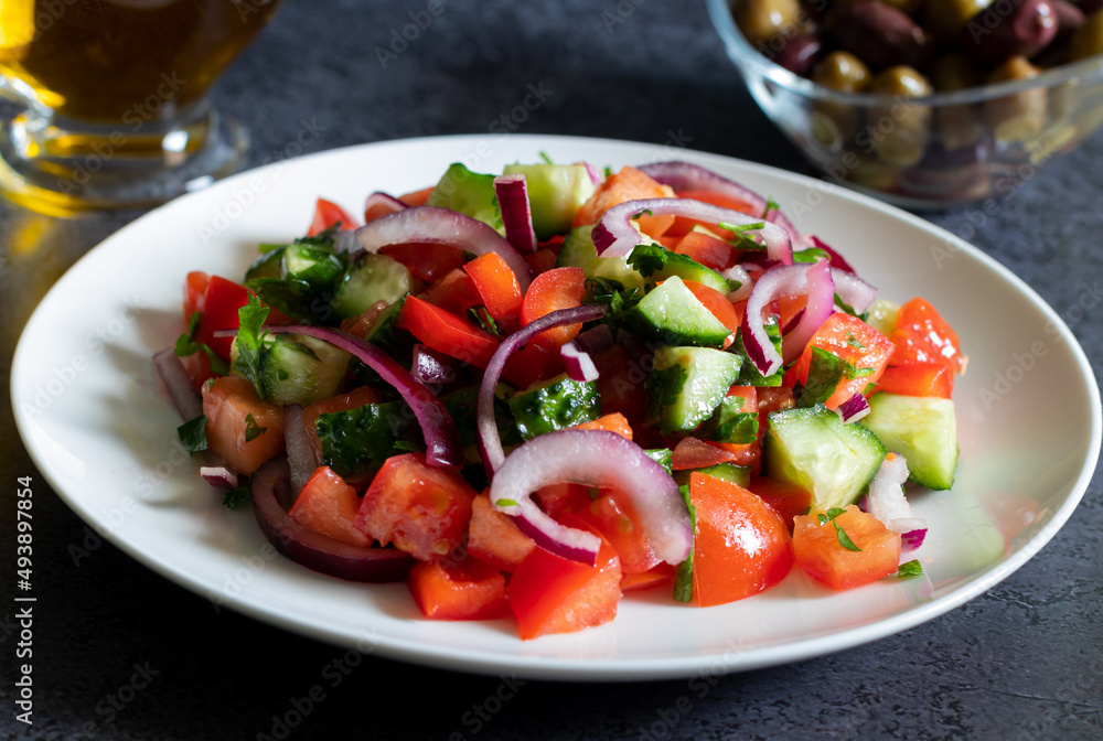 Salad with kalamata olives and olive oil on dark background close up