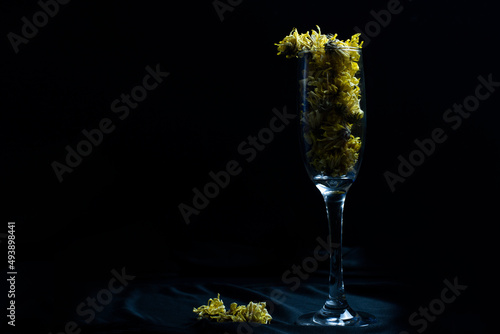 wine glass on a black background There are yellow dried flowers in the wine glass