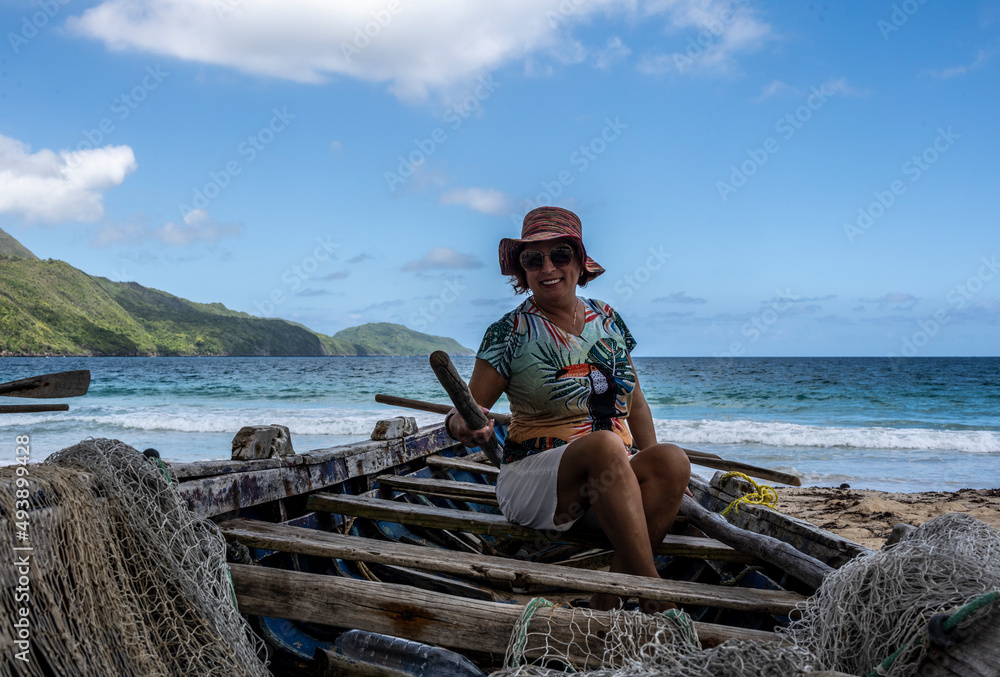 woman tourist near a fishing boat with a net on a sandy beach in the Dominican Republic 