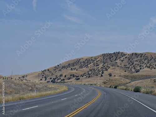 View along Highway 46 with sparse trees on the hillsides, California
