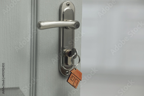 Key with house shaped fob in door lock, closeup. Space for text