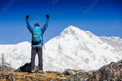 Hiker cheering elated and blissful with arms raised in the sky after hiking. Everest mountain on the backgroung - the world highest peak