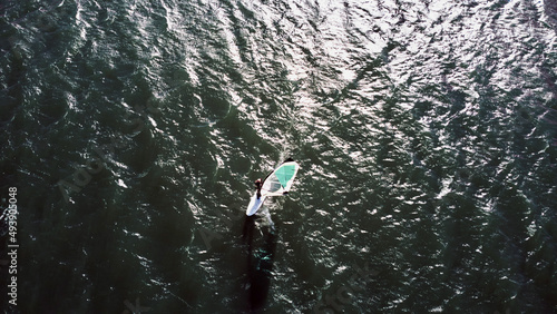 Surfboarding on a city urban river. Drone aerial photo.