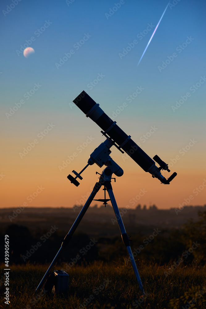 Silhouette of astronomical telescope and countryside.