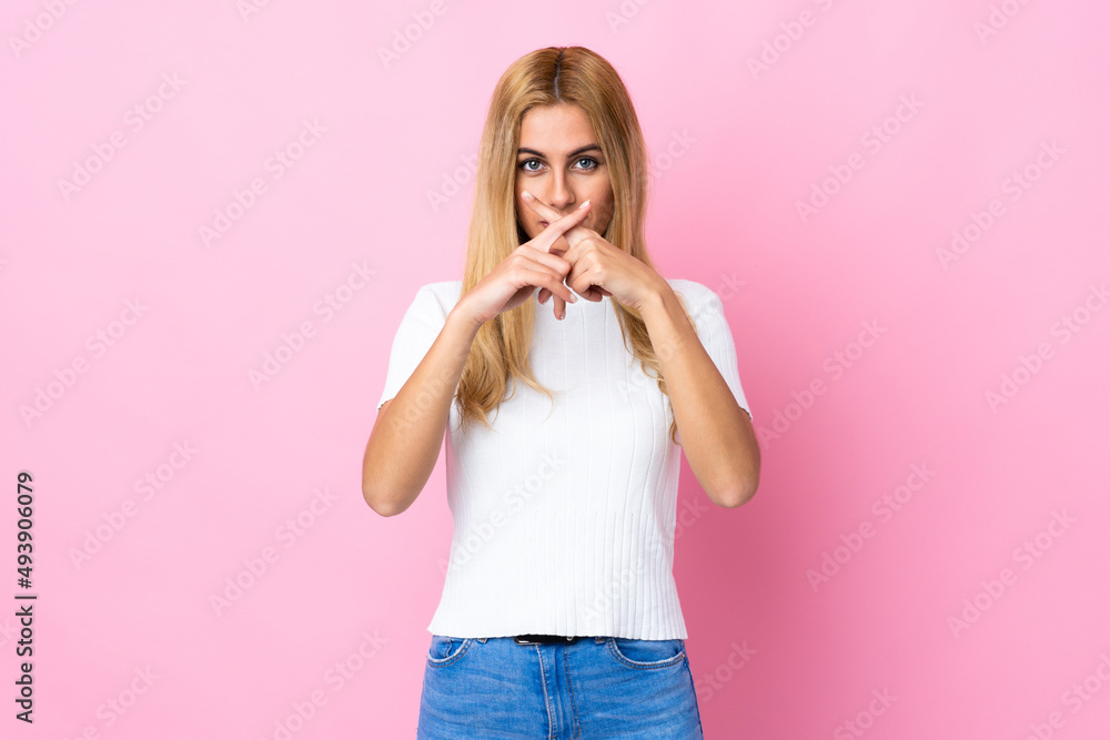 Young Uruguayan blonde woman over isolated pink background showing a sign of silence gesture Young Uruguayan blonde woman over isolated pink background showing a sign of silence gesture