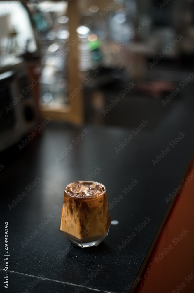 Ice coffee on a black table with cream being poured into it showing the texture and refreshing look of the drink