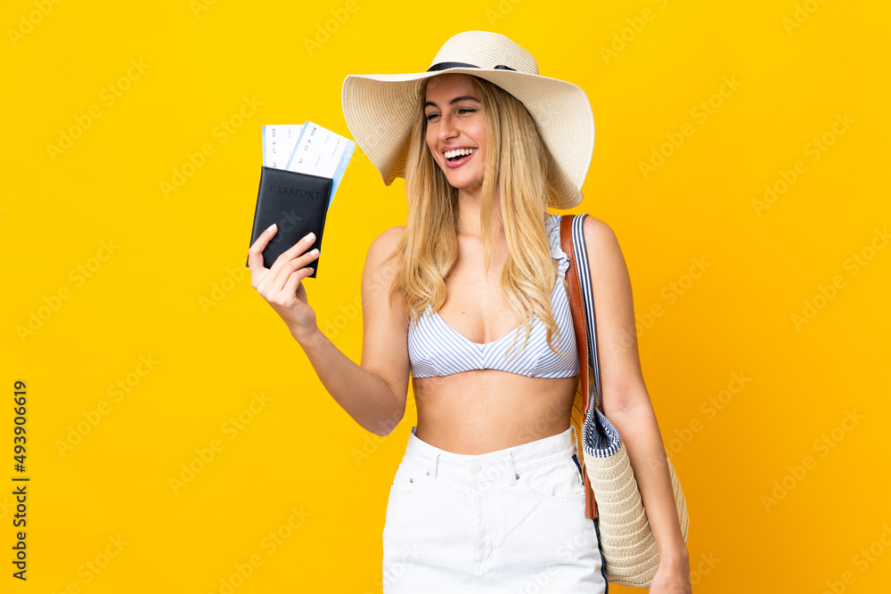Young Uruguayan blonde woman in swimsuit holding a passport over isolated yellow background with happy expression Young Uruguayan blonde woman in swimsuit holding a passport over isolated yellow background with happy expression