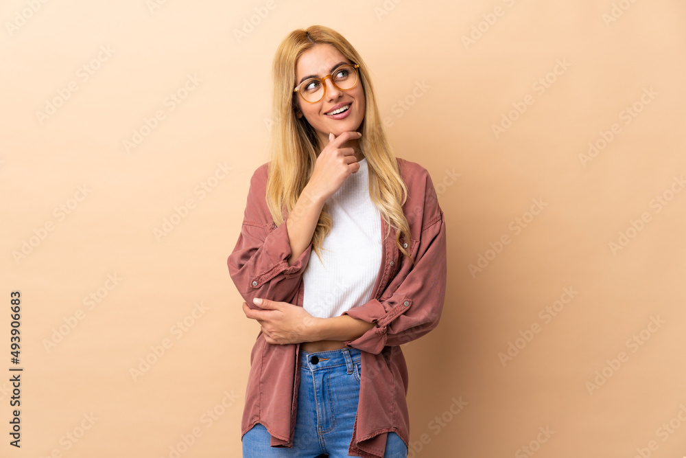 Young Uruguayan blonde woman over isolated background and looking up